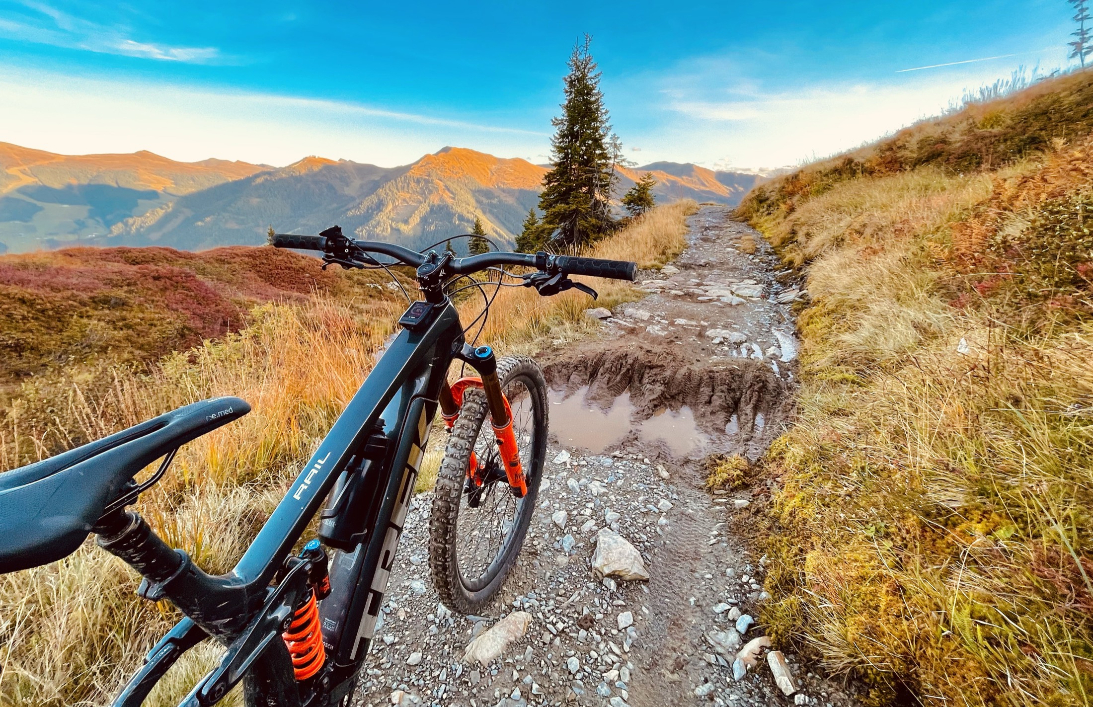 E-MTB-Cockpit auf einem alpinen Trail mit Bergpanorama